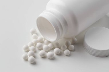 Homeopatik tedavi. Beyaz arka planda bir sürü haplı şişe, yakın plan.