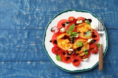 Balzamik sirkeli lezzetli salata, mozzarella ve çatal mavi ahşap masa, üst manzara. Metin için boşluk