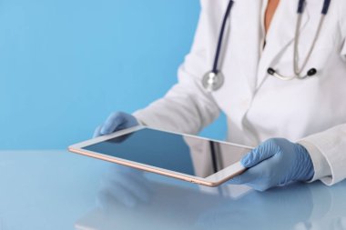 Tabletli doktor açık mavi arkaplanda, yakın görünüm