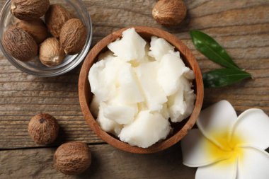 Doğal Shea tereyağı, fındık ve plumeria çiçeği ahşap masada, düz yatıyordu.