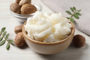 Shea tereyağı kasede ve fındık beyaz ahşap masada, yakın plan.