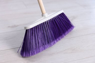 Ahşap zeminde parlak bir süpürge, yakın plan.