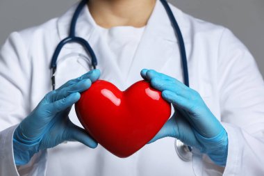 Gri arka planda kırmızı kalpli doktor, yakın plan.