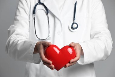 Gri arka planda kırmızı kalpli doktor, yakın plan.