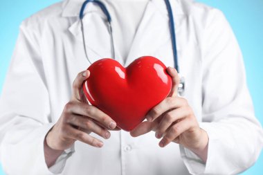 Açık mavi arka planda kırmızı kalpli doktor, seçici odaklanma