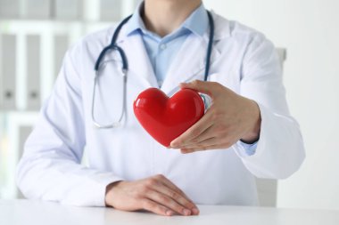 Klinikteki beyaz masada kırmızı kalpli doktor, yakın plan.