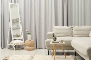 Güzel ayna, yan masa, dekoratif elementler ve şık oturma odasındaki kanepe.