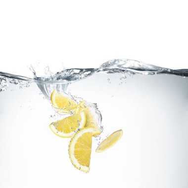 Beyaz arkaplanda suya düşen taze limonlar