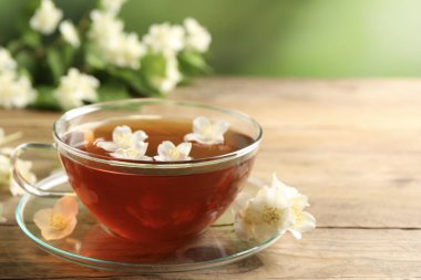 Sıcak yasemin çayı fincanda ve çiçekler ahşap masada, metin için yer