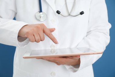 Mavi arkaplanda tableti olan doktor, yakın plan görünümü