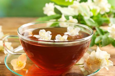 Sıcak yasemin çayı fincanda ve çiçekler ahşap masada