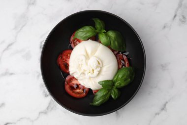 Lezzetli burrata peyniri, domates ve fesleğen beyaz mermer masa, üst manzara