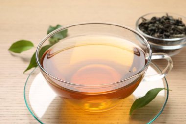 Yeşil çayı fincanda tazeleyen ve ahşap masada yapraklar, yakın plan