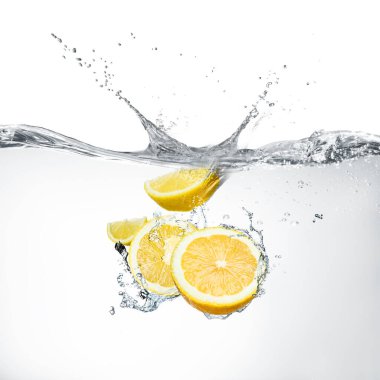 Beyaz arkaplanda suya düşen taze limonlar