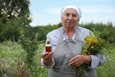 Tentür ve şifalı bitkilerle kıdemli kadın dışarıda, metin için yer var.