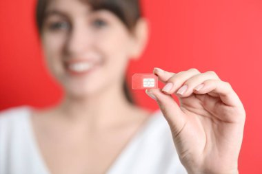Kırmızı arkaplanda SIM kartı tutan kadın, seçici odak
