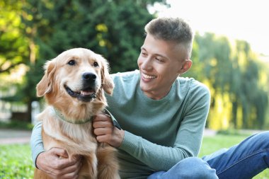 Parkta sevimli köpeğiyle genç bir adam.