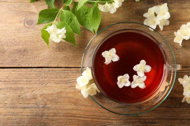 Sıcak yasemin çayı fincanda ve çiçekler ahşap masada, düz yerde. Metin için boşluk