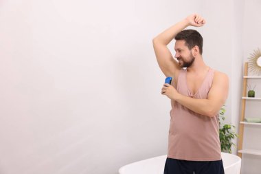 Gülümseyen adam evde katı deodorant sürüyor. Metin için boşluk