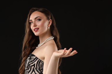 Siyah arka planda bir şey tutan güzel bir kadının portresi. Metin için boşluk