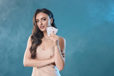 Poker oyunu. Açık mavi arka planda elinde iskambil kağıtları tutan hoş bir kadın. Metin için boşluk