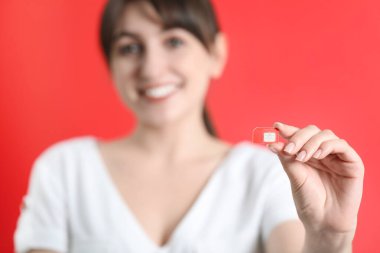 Kırmızı arkaplanda SIM kartı tutan kadın, seçici odak