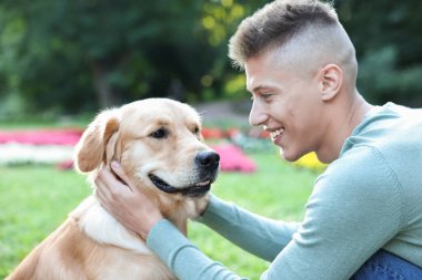 Parkta sevimli köpeğiyle genç bir adam.