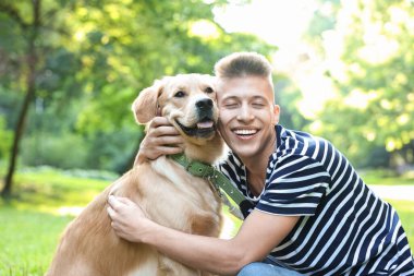 Parkta sevimli köpeğiyle genç bir adam.