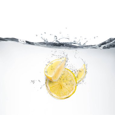 Beyaz arkaplanda suya düşen taze limonlar