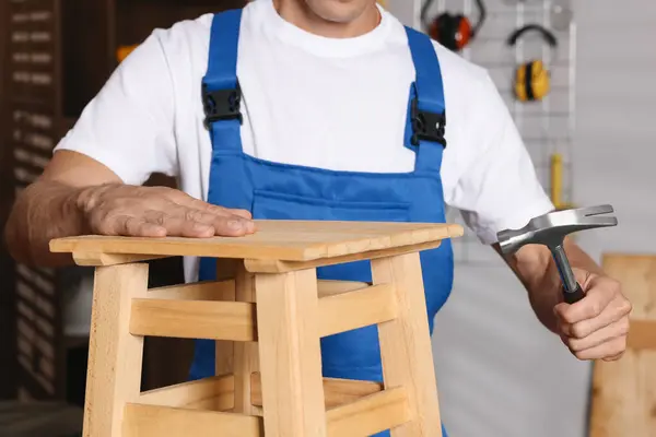 stock image Man repairing wooden stool with hammer indoors, closeup