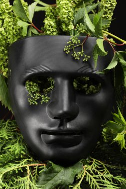 Tiyatro gösterisi. Siyah arka planda plastik maske ve çiçek dekoru