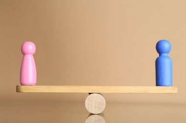 Cinsiyet eşitliği kavramı. Bej arka planda terazide erkek ve kadın figürleri