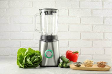 Blender ve ürünler beyaz tuğla duvara karşı ışık masasında