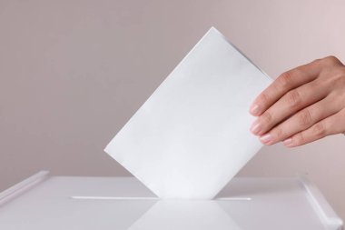 Kadın oyunu gri arka planda sandığa koyuyor, yakın plan.