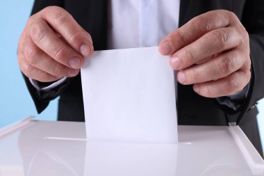 Adam oyunu açık mavi arkaplana karşı sandığa koyuyor.