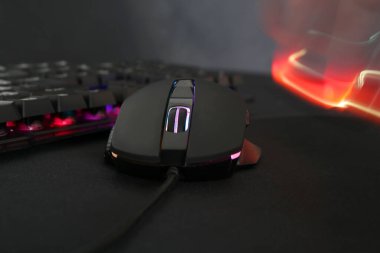 Koyu arkaplanda bilgisayar faresi ve RGB klavyesi, yakın plan