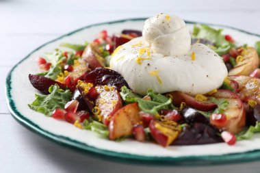 Beyaz ahşap masada taze burrata salatası, yakın plan.