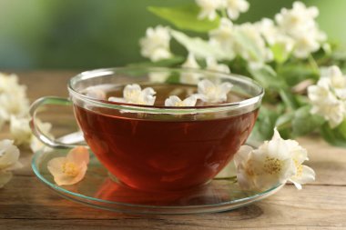 Sıcak yasemin çayı fincanda ve çiçekler ahşap masada