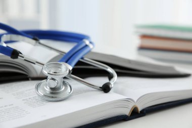 Bir tıbbi steteskop ve beyaz masanın üzerinde kitaplar, yakın plan.