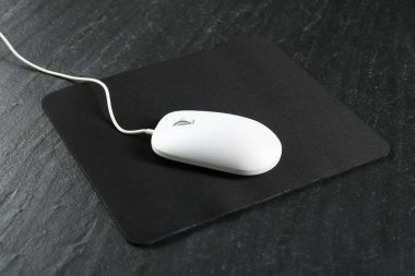 White wired mouse and mousepad on black textured table clipart