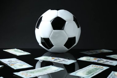 Siyah arka planda futbol topu ve dolar banknotları