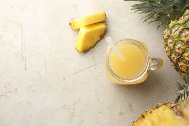 Mason kavanozunda nefis ananas suyu ve gri desenli masada taze meyveler, düz yatak. Metin için boşluk