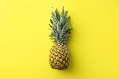 Sarı arka planda taze, olgun bir ananas.