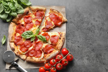 Lezzetli pepperoni pizza, kesme makinesi ve malzemeler gri masada, düz yayılmış. Metin için boşluk