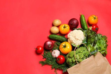 Vejetaryen ürünlerin teslimatı. Kırmızı arka planda farklı sebzeli çanta, üst manzara.