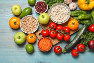 Açık mavi ahşap masa üzerinde farklı vejetaryen ürünler.