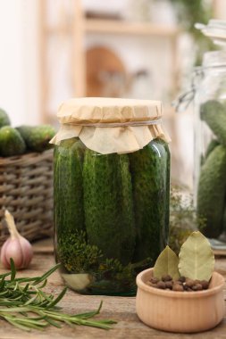 Kavanozda salatalık turşusu ve ahşap masada baharatlar, yakın plan.