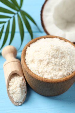 Kase içinde taze hindistan cevizi unu, kepçe, fındık ve palmiye yaprağı açık mavi ahşap masa üzerinde