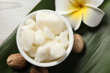 Tabakta Shea yağı, beyaz ahşap masada çiçek ve fındık, düz yatıyordu.