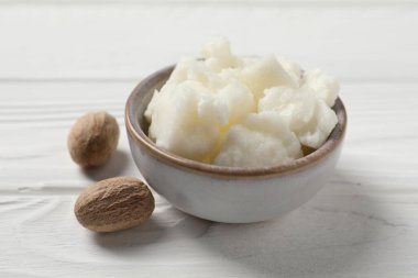 Shea tereyağı kasede ve fındık beyaz ahşap masada, yakın plan.